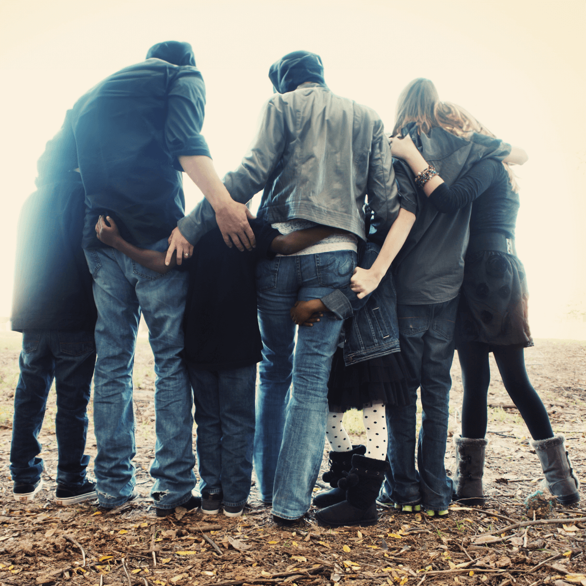 Chosen family shown from behind in circular group hug